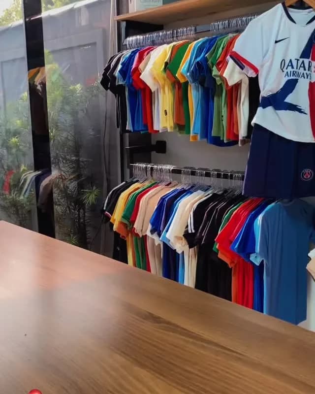 A arara da loja, com as polos e camisetas penduradas por cor